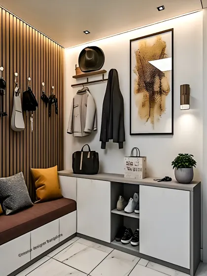 This foyer design features a practical bench with shoe storage underneath and a row of hooks for coats and bags. The abstract art and warm lighting create a welcoming and stylish first impression.