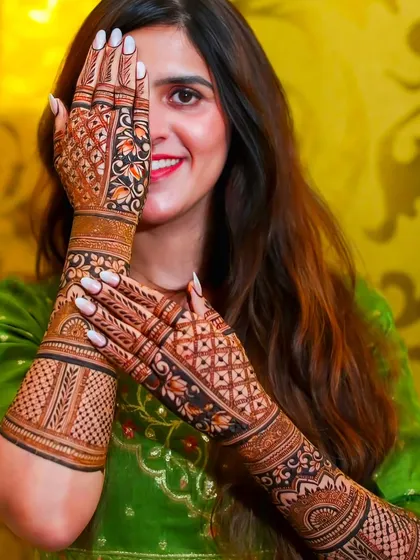 A happy bride is my best advertisement. Here you can see how the full-arm mehndi looks with the bridal outfit, creating a complete and stunning look for your wedding photos. The design features intricate jaali work and floral patterns.
