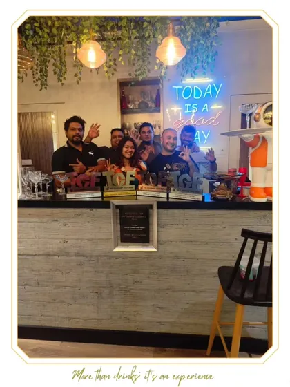Our team behind the bar with the Platinum Award from the WeddingSutra Influencer Awards, under a "Today is a good day" neon sign.