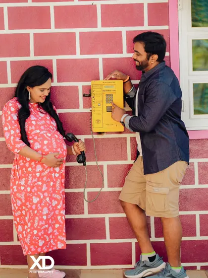 A playful and nostalgic shot of a couple using a vintage yellow payphone as a prop.