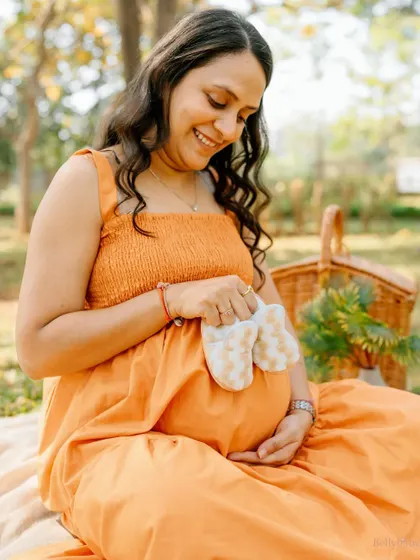 A close-up on those adorable little shoes held against the bump. It's a sweet reminder of the tiny feet that will soon be filling them.
