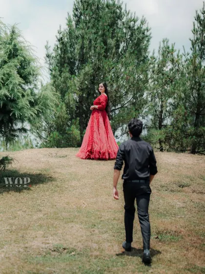 The groom walks towards the bride, who stands on a hill with pine trees in the background. This shot creates a sense of anticipation and highlights the beauty of the location.