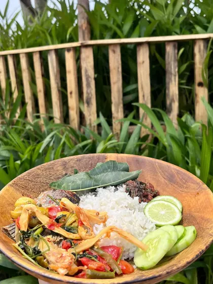 Our fish and bitter eggplant meal, served in a wooden bowl against a backdrop of lush greenery. It's a reminder of the close connection between our food and the land it comes from.