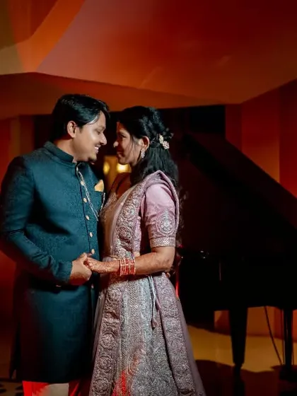 A couple shares a dance by a grand piano at their reception, creating a scene of classic romance and elegance.