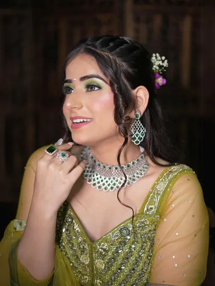 A close-up of the green and yellow floral lehenga, highlighting the matching green eyeshadow and jewelry.