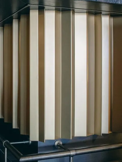 A close-up of the fluted metal bar front, showcasing the attention to materiality and texture. The alternating metallic tones create a subtle, rhythmic pattern that adds a touch of industrial chic to the design.