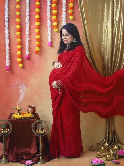 The flowing red saree against a warm, glowing backdrop creates such a dreamy and powerful image. The smoke from the diya adds a touch of sacred magic to this maternity portrait.
