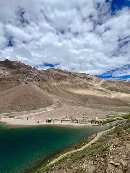 An aerial view of Chandratal Lake, showing its crescent shape and the people on its shore. This perspective really highlights why it's called the "Moon Lake."