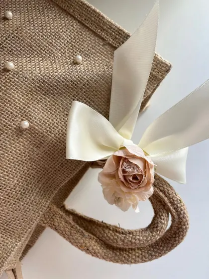 A close-up of the delicate pearl, flower, and ribbon detailing on our custom jute bags. This shows the level of craftsmanship we put into every single gift.