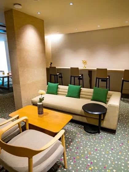 This breakout lounge at the Elevate Clubhouse offers a more relaxed, informal seating area. The combination of a sofa, armchairs, and high-top seating caters to different group sizes and activities, from casual chats to quiet work.