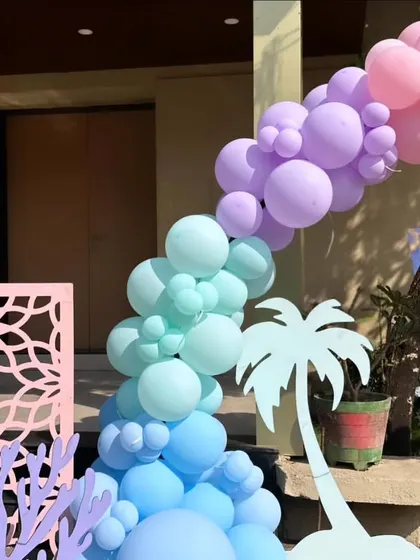 A beautiful pastel balloon garland for a pre-wedding pool party, featuring soft gradients and decorative cutouts like palm trees and coral.