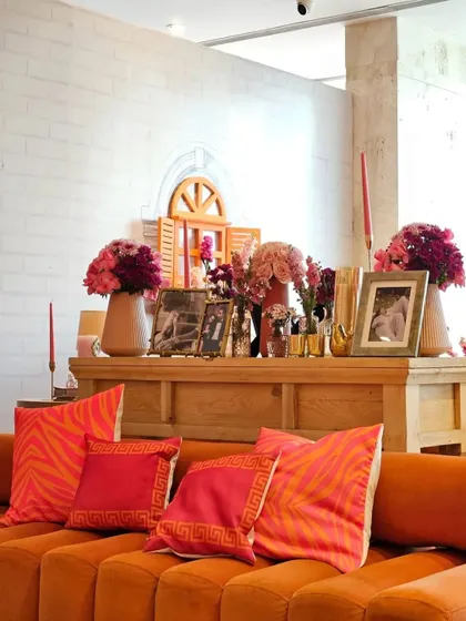 A cozy seating nook from the 'Rang De Mohabbat' Sangeet, with vibrant orange sofas and personalized photo frames. We create these smaller, intimate corners within a larger event for guests to relax and connect.