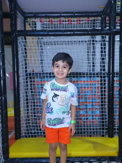 A smiling boy stands inside one of our netted play structures, safe and happy.
