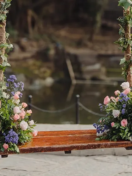 A beautiful floral swing decorated with purple and pink flowers, providing a romantic photo spot by the water.
