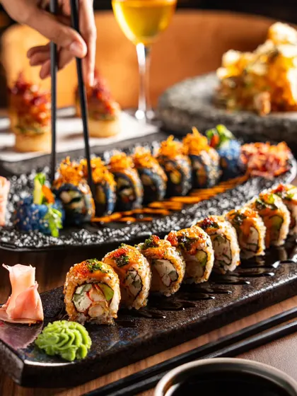 A dynamic shot of chopsticks picking up a piece of sushi. This action adds life to the scene and makes the viewer imagine taking a bite.