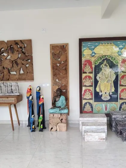 A display of various decorative items, including wooden parrot statues, a Buddha on a wooden block, and traditional Indian paintings.