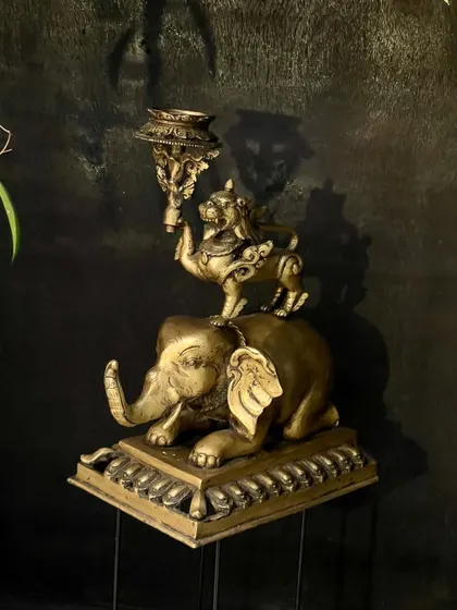 The Tibetan-style brass candle stand, viewed from above. This angle shows the detailed carving on the candle holder itself, held up by the powerful lion.
