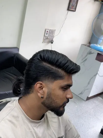 A side view of the low-fade mullet with a ponytail, showing how the fade blends into the longer hair.