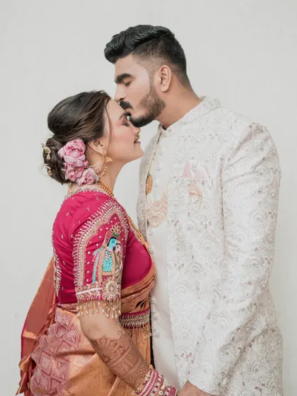A tender moment between the bride and groom. The groom's kiss on her forehead is a classic wedding shot, and her makeup looks flawless and beautiful.
