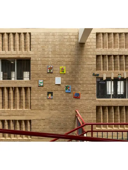 The textured brick walls of Buddhi School serve as a backdrop for student artwork, turning the building's corridors into a living gallery.