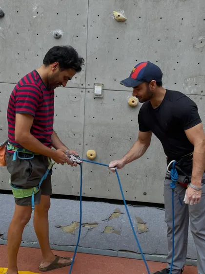 A close up of an instructor teaching a climber how to properly set up their belay device. We ensure everyone masters these skills in a safe, controlled environment.