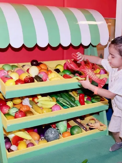 A young boy picks out a toy lobster from our fully stocked pretend supermarket.