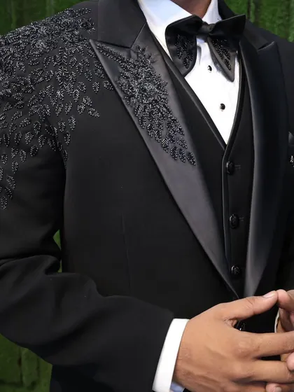 A detailed shot of our black tuxedo, focusing on the fit and the fine embroidery. You can see the quality in the satin lapels and the sharp cut of the suit.