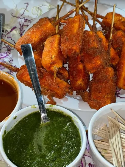 Paneer fingers coated in a crispy batter and fried until golden, served on skewers with chutneys.