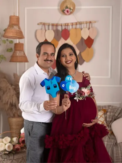 A sweet couple's portrait in the boho setup, announcing they're expecting a boy. The deep red gown is a beautiful, bold choice.