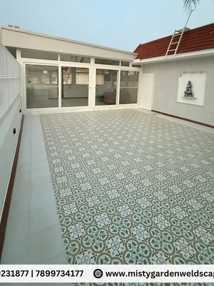 The exterior of the terrace room during the day, highlighting the clean white finish of the structure, the elegant patterned flooring of the patio, and a privacy lattice on the side.