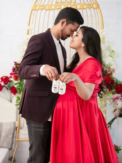 An intimate pose where the couple touches foreheads, holding tiny baby shoes between them. It’s a beautiful, symbolic portrait of their shared journey into parenthood.