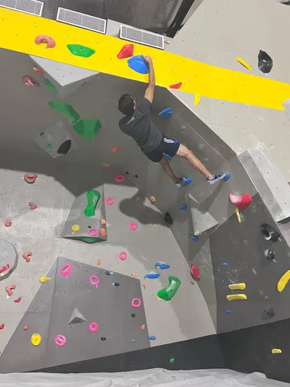 Our facility is your indoor playground for adventure. This climber is reaching for a hold on one of our traverse routes, a great way to build endurance and practice footwork.