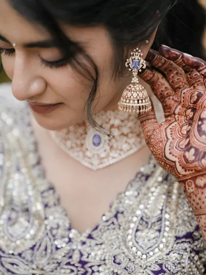 A close-up shot focusing on the bride's stunning earring and the intricate henna on her hand, highlighting the beautiful details.