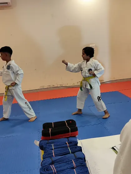 Two young students practice their fundamental stances and punches during a belt grading exam.