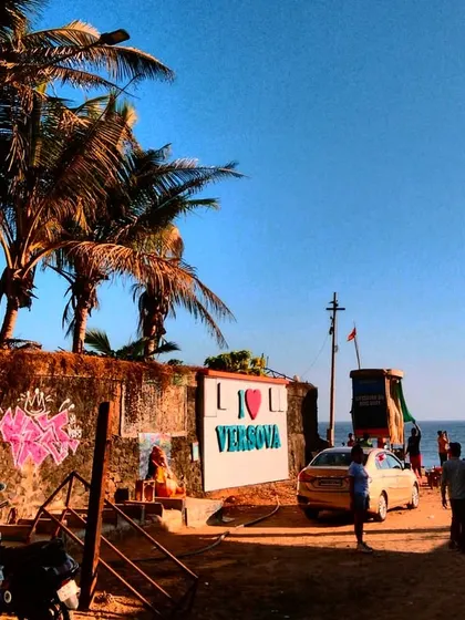 A wider view of my graffiti at Versova beach, with the "I Love Versova" sign and the sea in the background. My art is made to be part of the city's landscape.