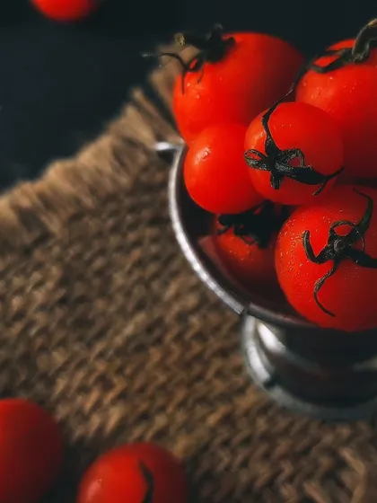 A close-up on the cherry tomatoes, focusing on their bright color and the texture of the burlap. This macro shot highlights the simple beauty of fresh ingredients.
