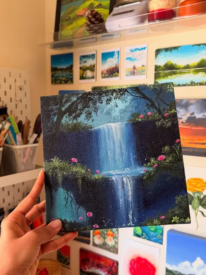 Holding my magical blue waterfall painting in my studio. You can see some of my other landscape art in the background, which always inspires me.