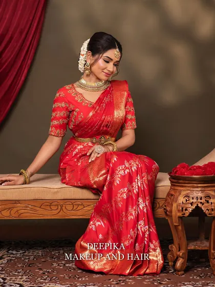 A bride seated gracefully in a stunning red silk saree. This look is a beautiful example of a classic Maharashtrian or South Indian bridal style.