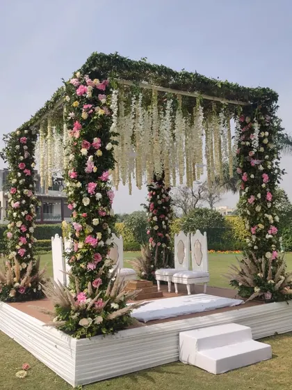 A closer view of a floral mandap, showcasing the detail of the flowers wrapped around the pillars and the hanging wisteria from the roof.