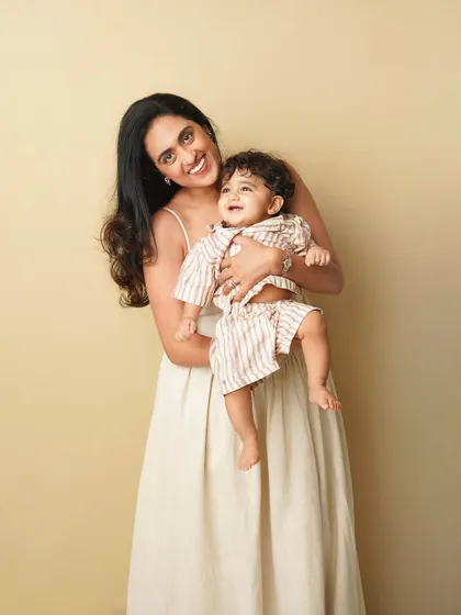 A mother and her toddler son share a joyful moment. The warm, neutral background and their happy expressions create a timeless and heartwarming portrait.