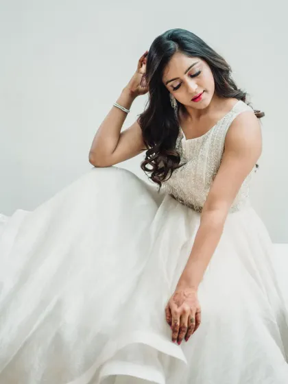 A soft and serene portrait in a white embellished gown. The model's gentle pose and the flowing fabric create a feeling of calm and elegance in this high-key shot.