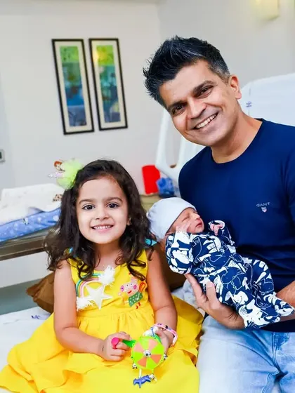 Welcoming the new baby at the hospital. This photo captures the proud father and excited big sister holding the newest member of their family, a beautiful first family portrait.