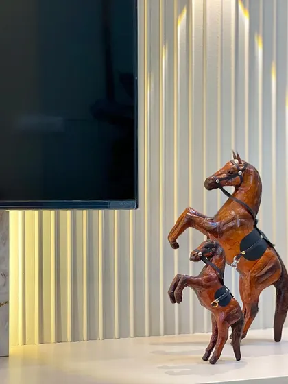 A close-up of the decor on the TV console, showing how I use small details like these leather horse figurines to add personality and a touch of sophistication to the living space.