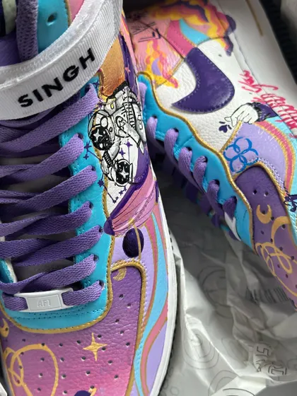 A close-up of the BTS-themed custom Air Force 1s. You can see the intricate details of the astronaut riding the whale through a cosmic sky.