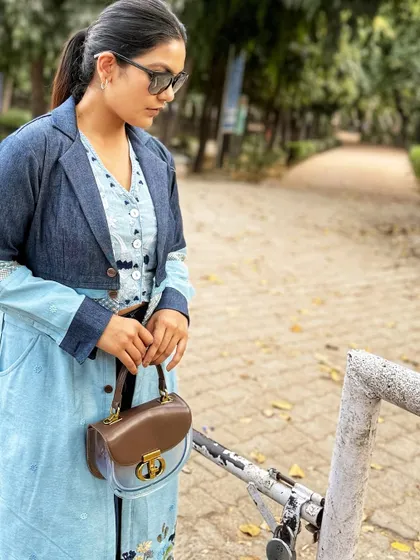 A detail shot of the brown and clear handbag, which adds a sophisticated touch to the casual, layered denim outfit.
