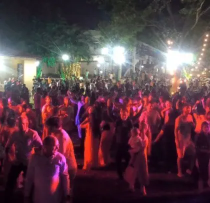 The crowd goes wild at the corporate Holi party, dancing under the open sky with a full lighting and sound setup.