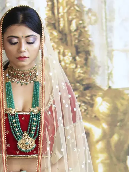 A closer look at the red velvet bridal lehenga, highlighting the deep V-neckline of the blouse and the sheer net dupatta. The richness of the velvet fabric gives the outfit a truly luxurious feel.
