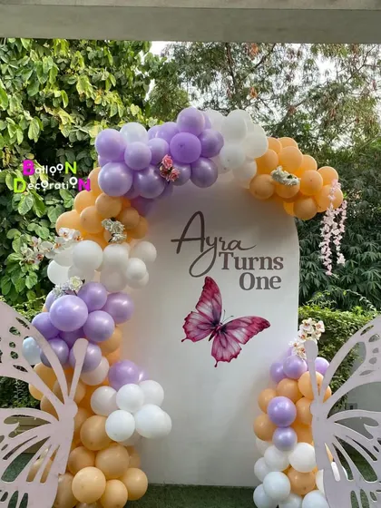 The beautiful contrast of the pastel balloons and butterfly wings against the lush greenery makes for perfect party photos.