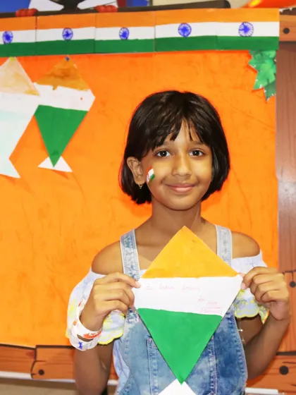 A girl with a tricolor painted on her cheek shows off her handmade kite. Face painting and themed crafts are some of the most popular activities during our festive events.