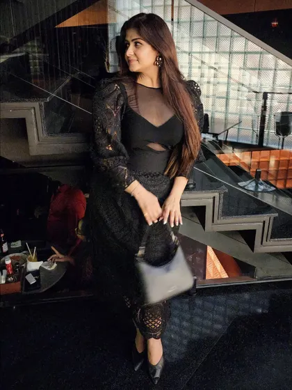 A different angle of the black dress, showing its intricate texture and modern cutouts. It defines, rather than blends in.